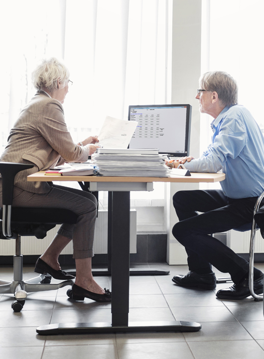 Salesperson and Buyer sit at desk during negotiations