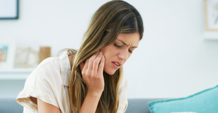 Woman holding jaw in pain.