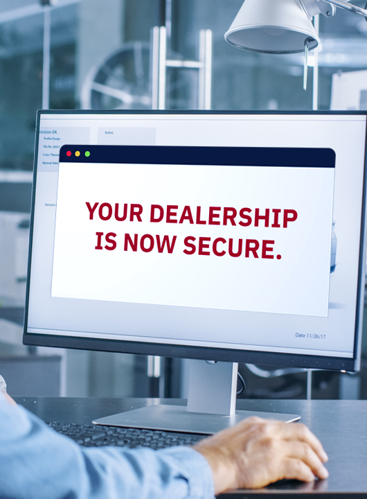 Sales person working on a computer with a message that says "Your dealership is now secure."