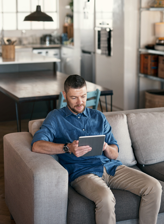 Man sitting on couch with tablet in hand using Gubagoo