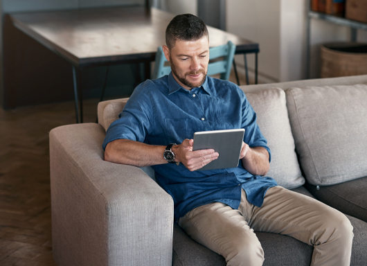Man sitting on couch with tablet in hand