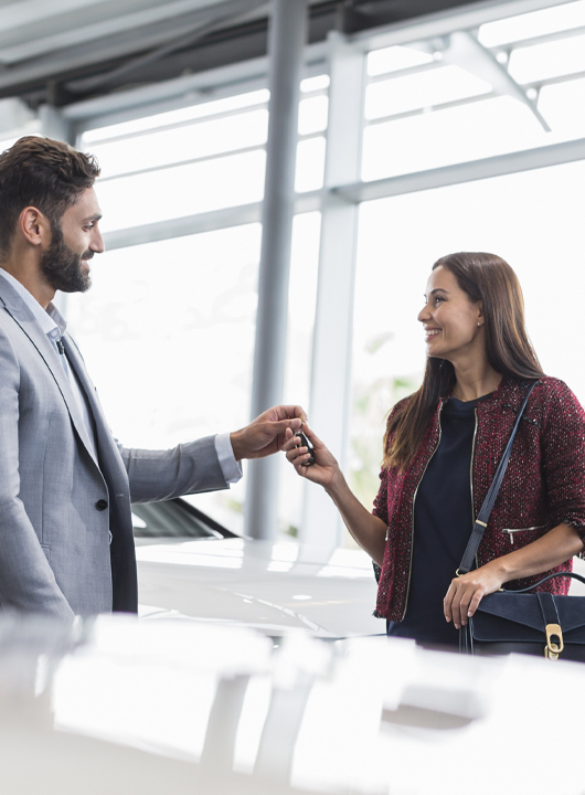 Sales person handing over new car keys to a customer.