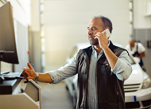 Mechanic on phone with customer in service bay.