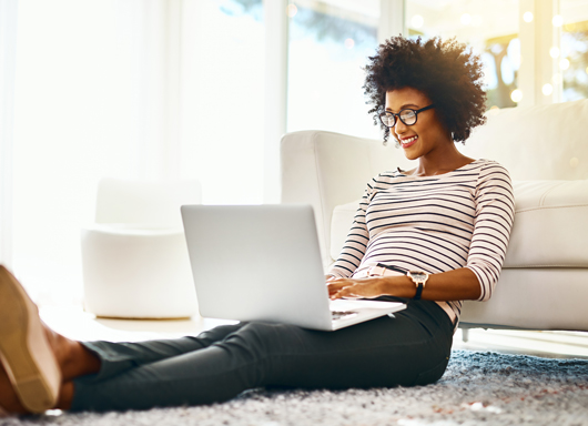 Woman smiling reading an enewsletter on her laptop.