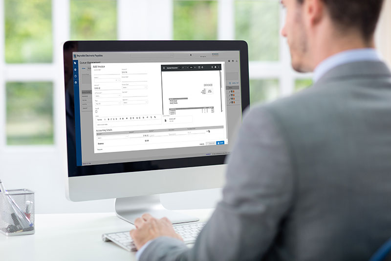 Man viewing an invoice on computer in dealership business office