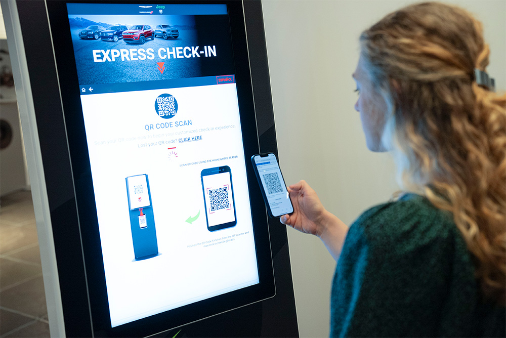Image of a woman scanning a QR code on a GoMoto kiosk screen