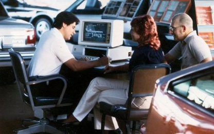 Photo of a car salesman with two customers in dealership in 1960