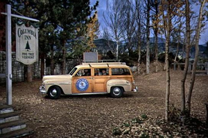 Old-time white and orange car sitting in a wooded area