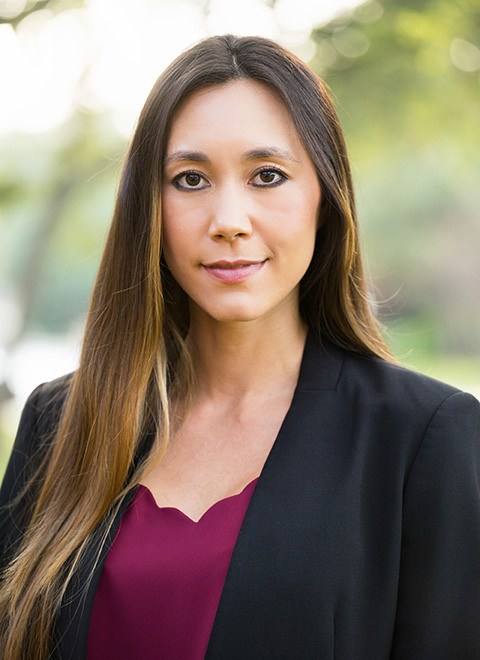 Woman with long dark hair wearing a purple top with a black jacket