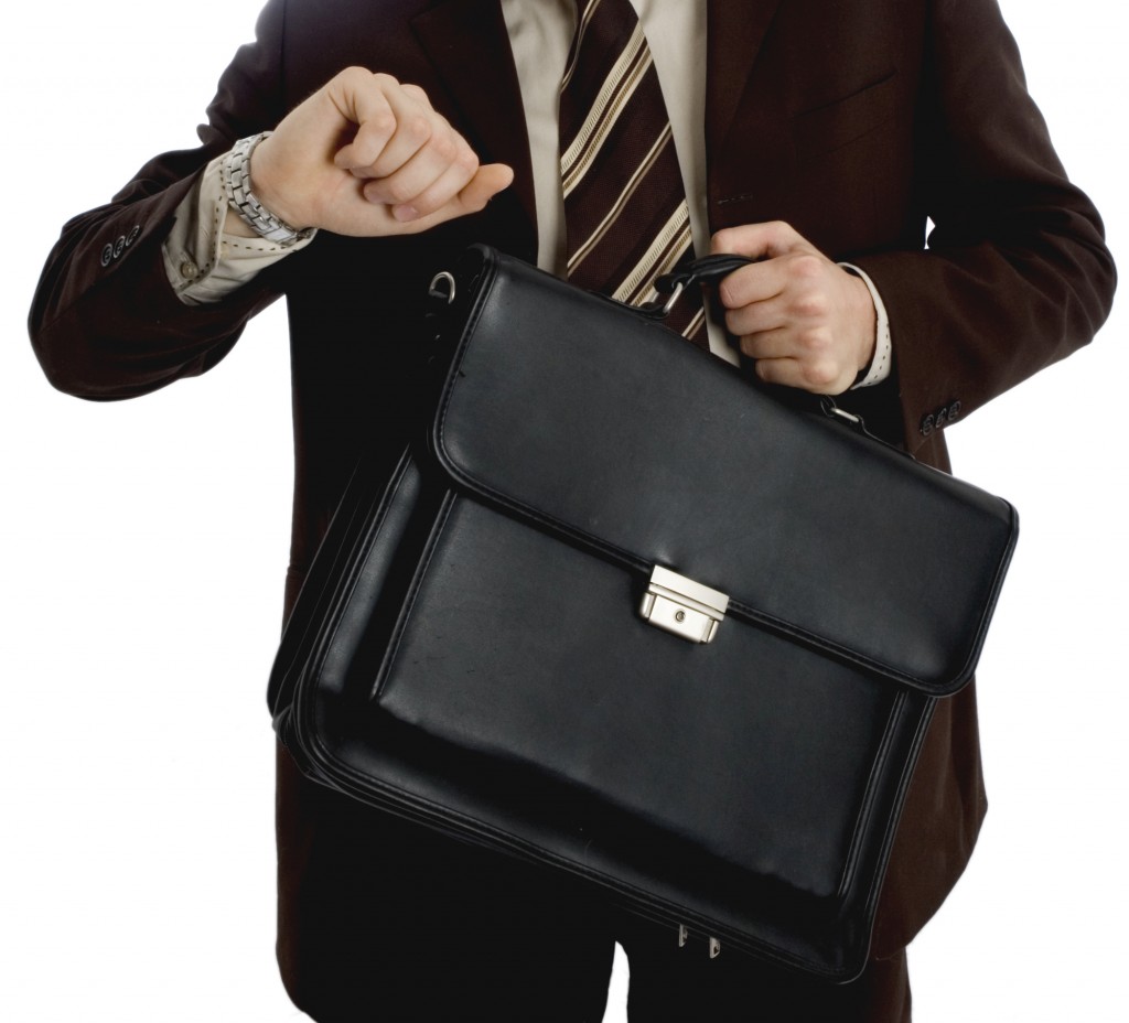 Man in suit holding a briefcase and looking at his watch