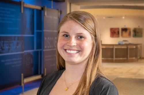 Headshot of a young woman with brown hair and a black top.