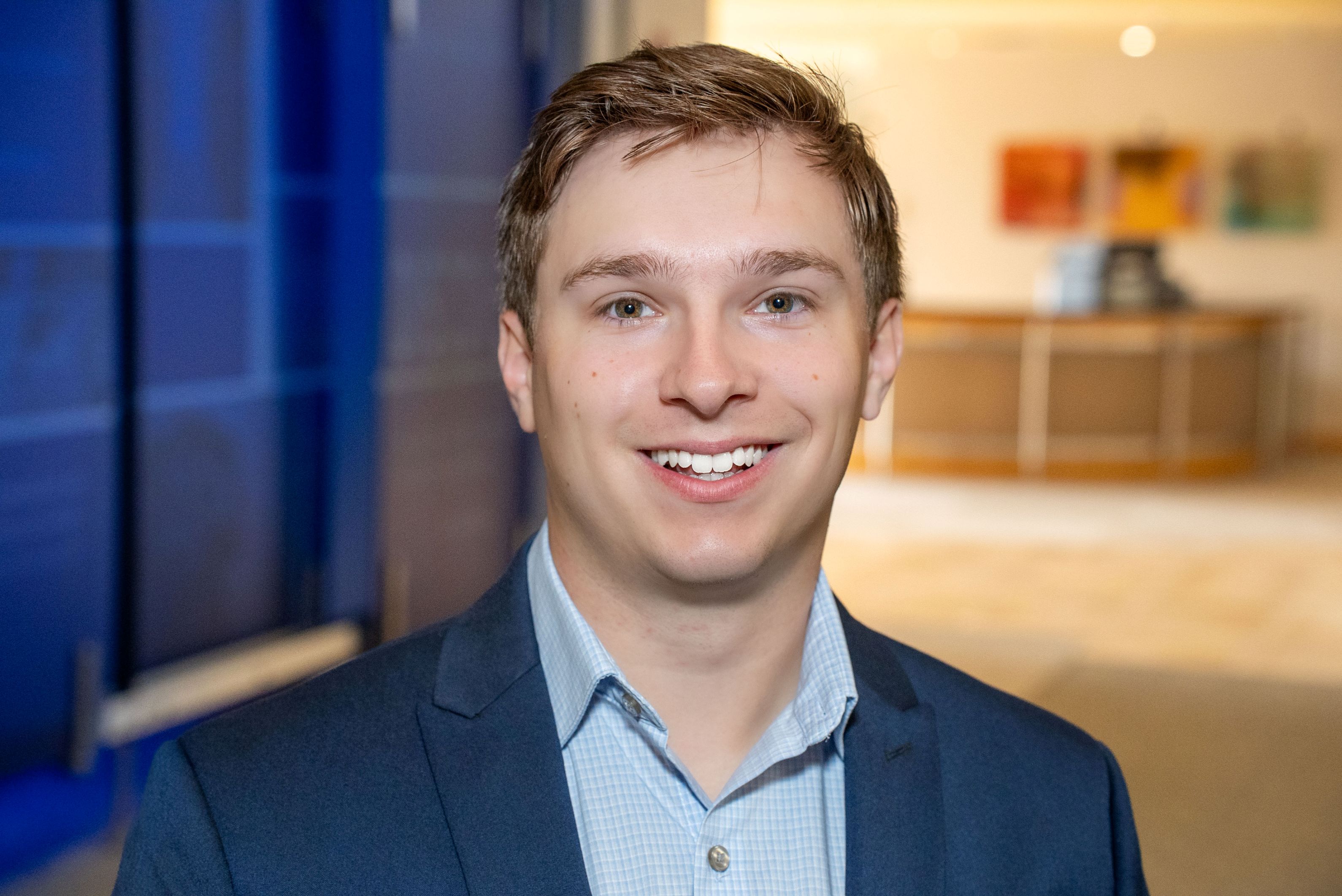 Headshot of young man with brown hair, in a blue shirt and blazer.