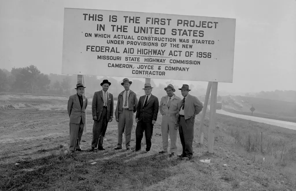 Photograph of men standing in front of highway act sign in Missouri