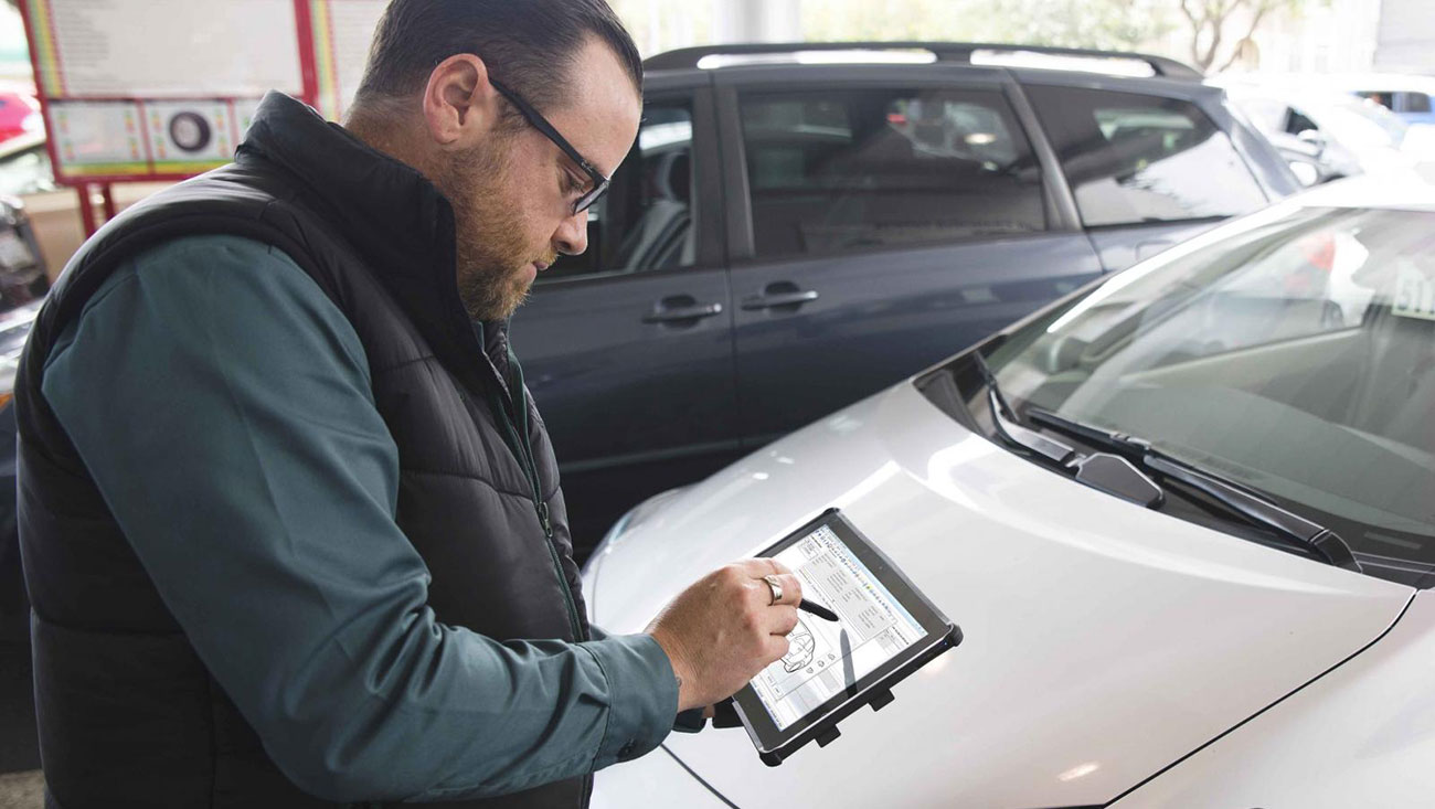 Man performing vehicle inspection using a tablet.